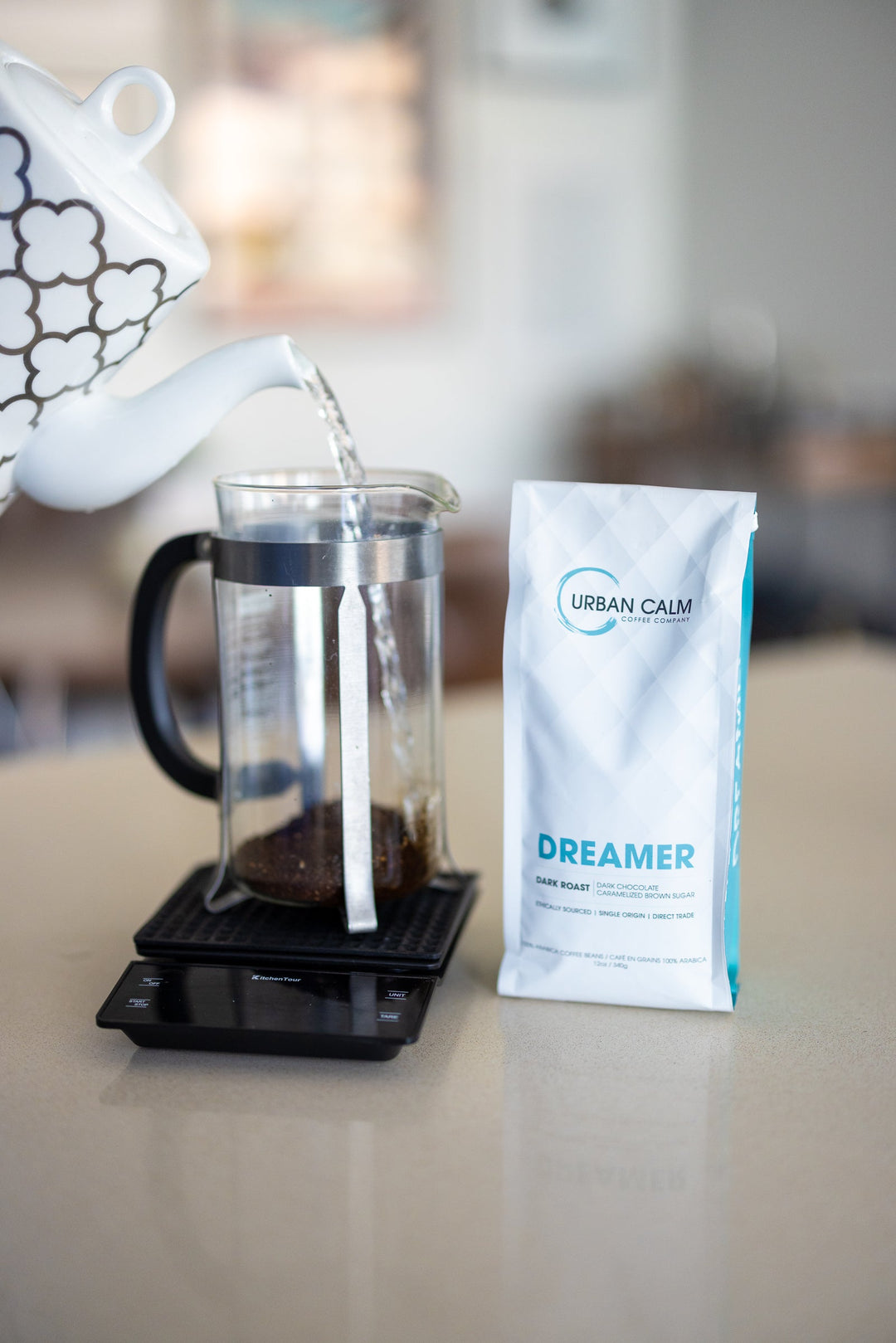 French press with light roast coffee on a table with a mug