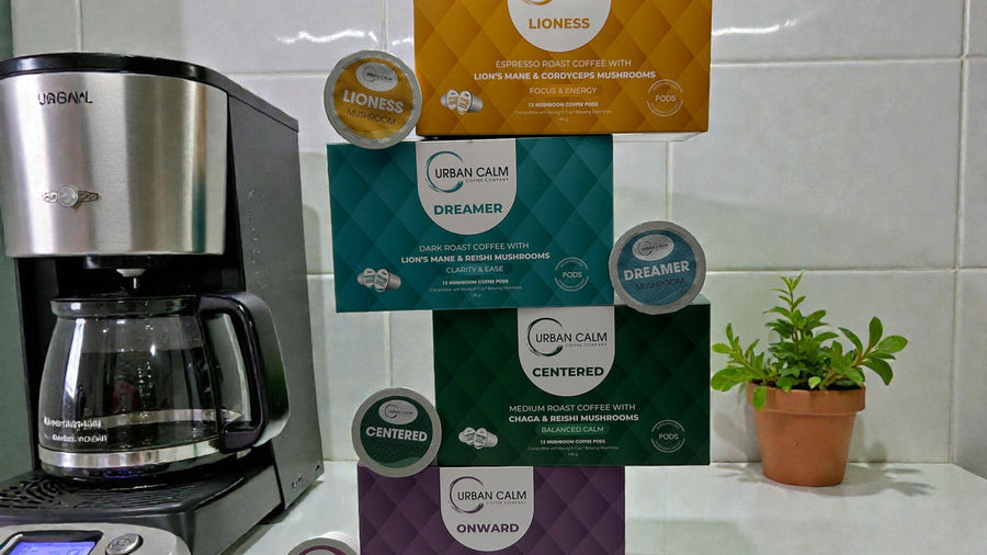 Urban Calm Onward, Centered, Dreamer and Lioness mushroom coffee K-Cups beside a single-serve brewer