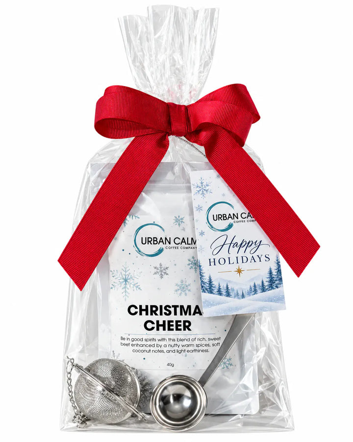 Urban Calm holiday loose-leaf tea gift set wrapped with a red bow and a Happy Holidays tag on white background