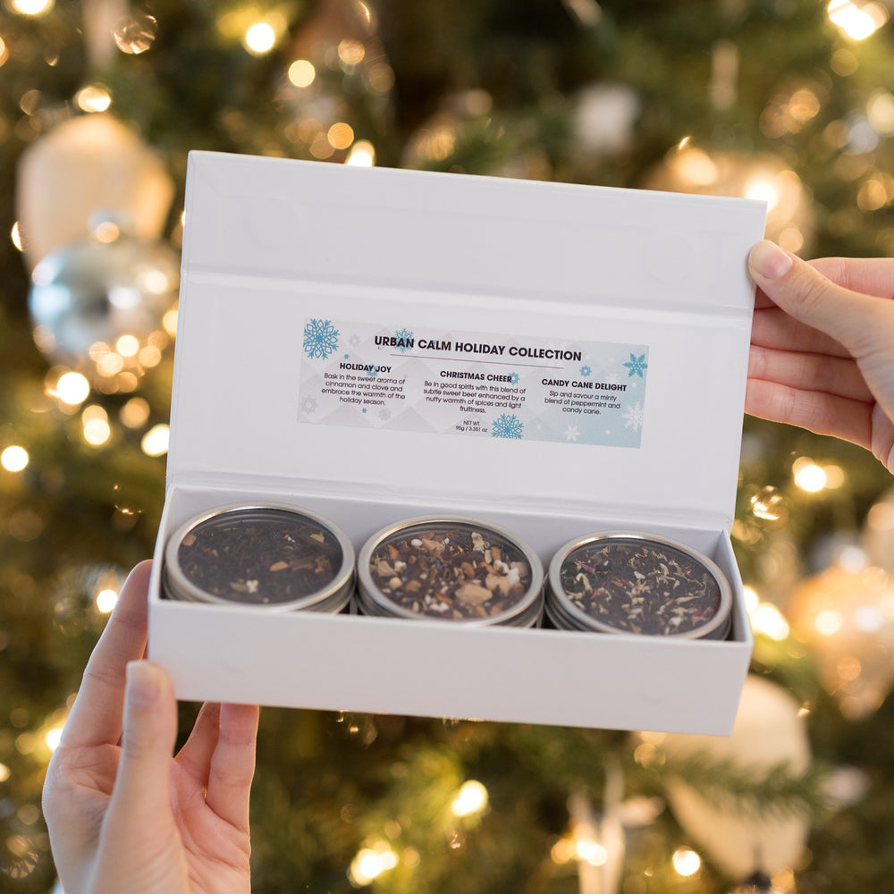 Winter Bliss Tea Trio open gift box with three tea tins by a Christmas tree
